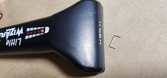 Little Wizard metal detector with LED indicators lit detecting a single staple on a wood surface