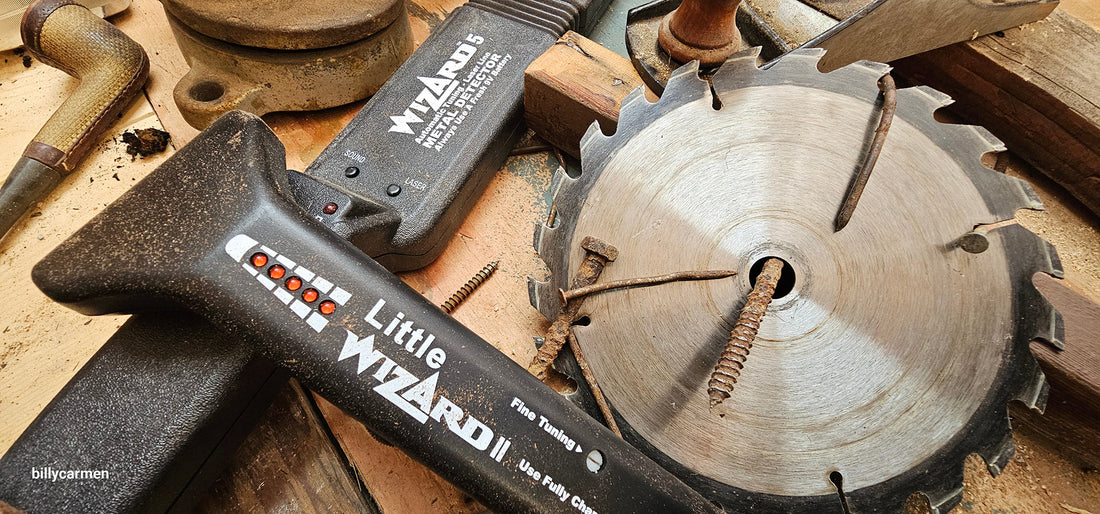 Lumber Wizard 5 and Little Wizard 2.5 metal detectors on a workshop bench alongside a damaged saw blade and rusty nails