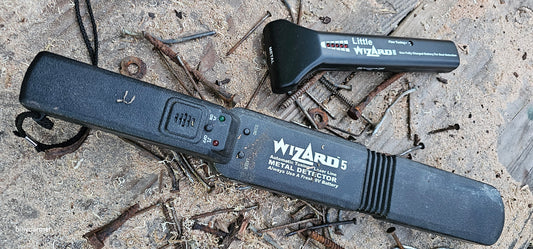 Wizard 5 and Little Wizard metal detectors laying among rusty nails and metal debris on a concrete surface