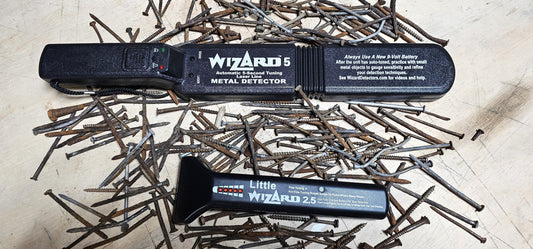 Wizard 5 and Little Wizard 2.5 woodworking metal detectors surrounded by rusty nails on a workbench