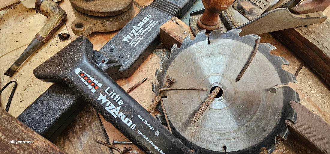 Wizard 5 and Little Wizard metal detectors next to a damaged circular saw blade and rusty nails on a workshop bench