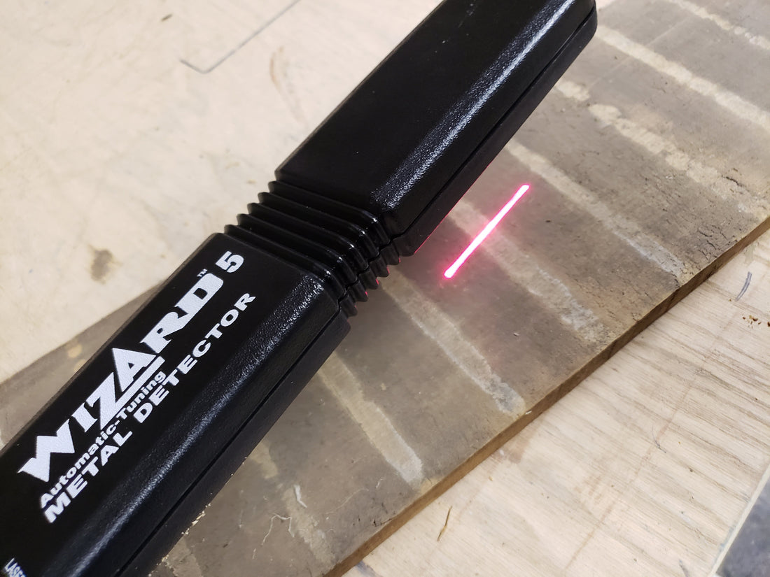 Lumber Wizard 5 projecting red laser line onto a reclaimed wood plank during metal detection scan